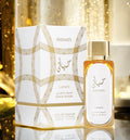 A bottle of HAYAATI Laitafa Gold Elixir Eau de Parfum next to its white and gold patterned packaging box, set against a festive, warm golden bokeh background.
